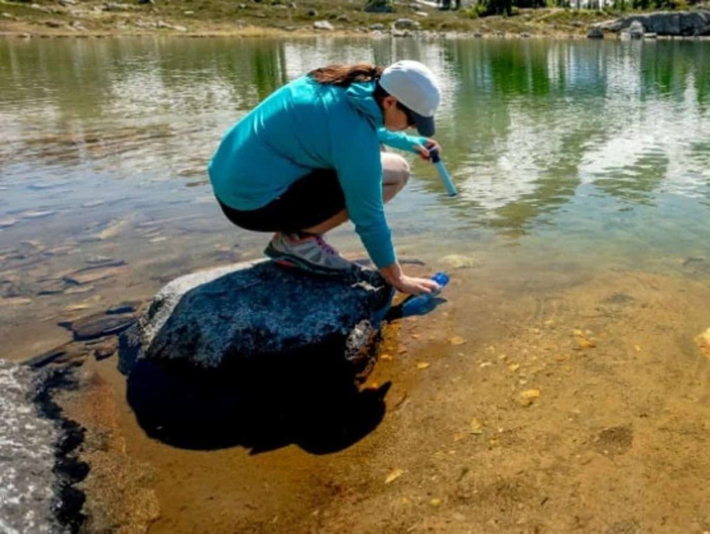 woman using a lifestraw to drink clean water