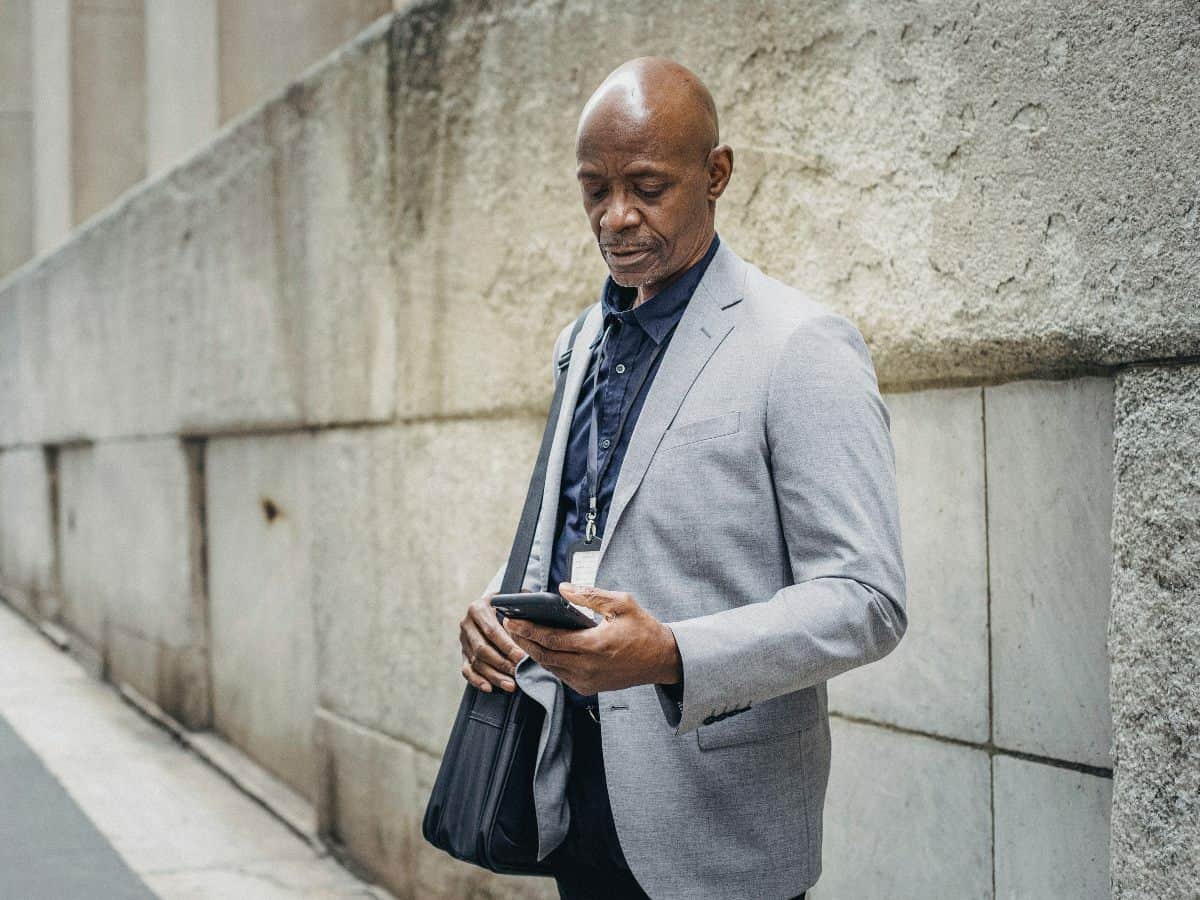 man standing outside looking at his cell phone