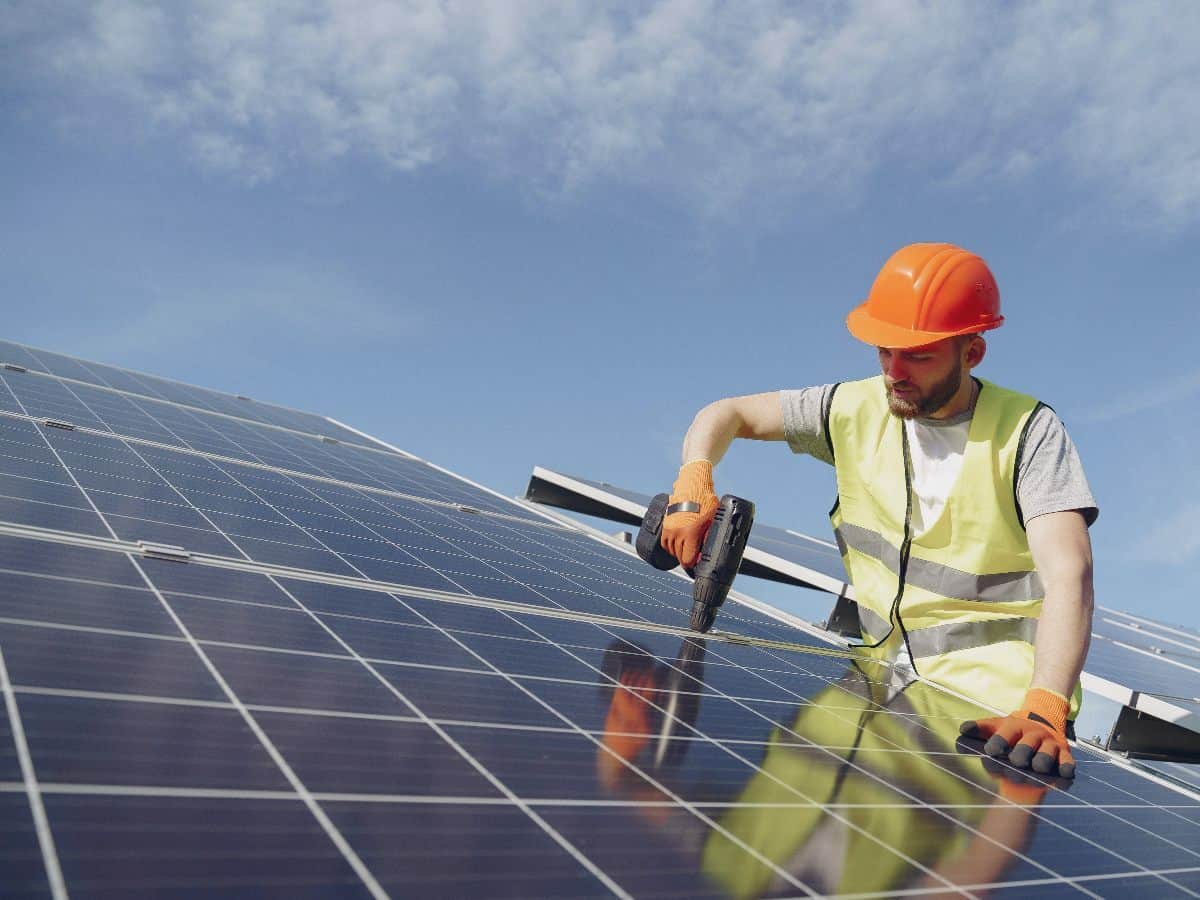 man fixing solar panel with professional drill