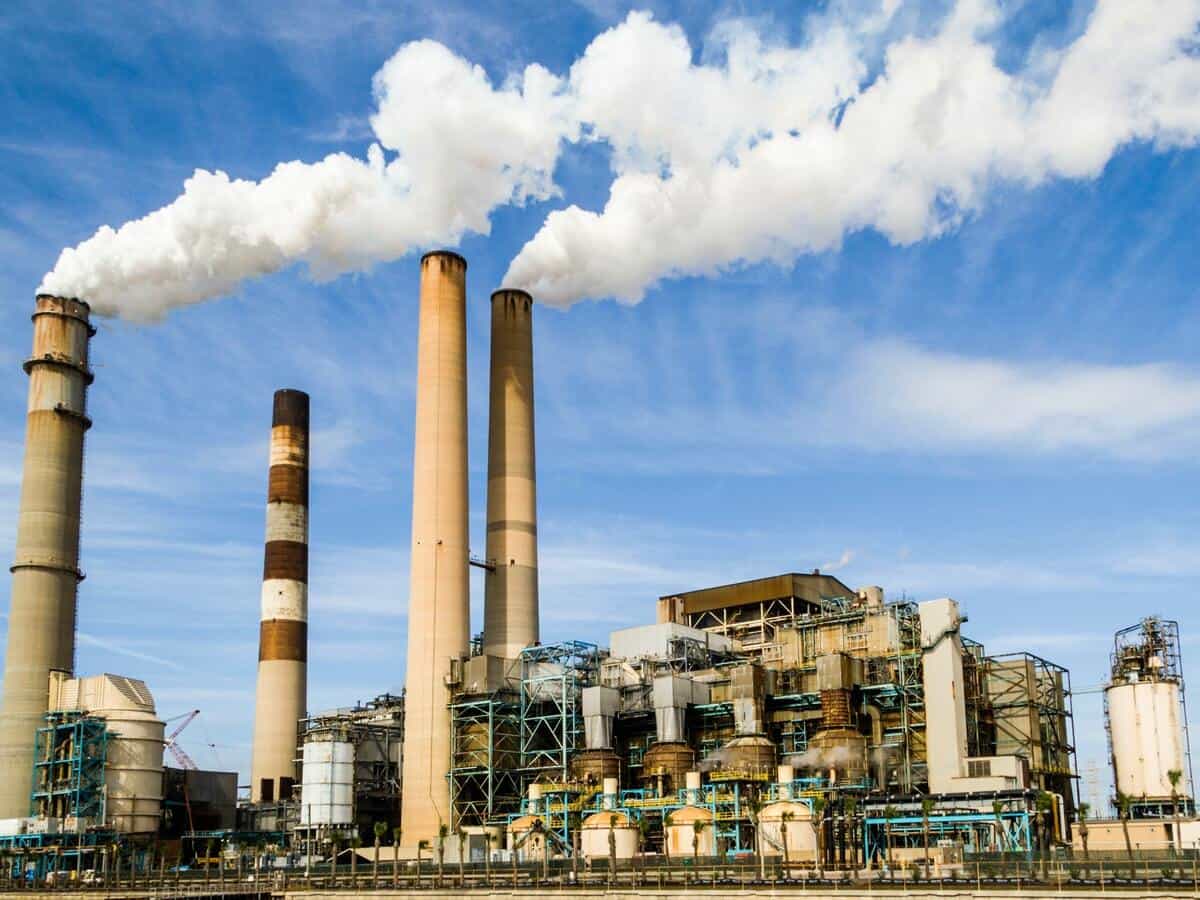 A power plant factory with clouds of smoke being released from the top.