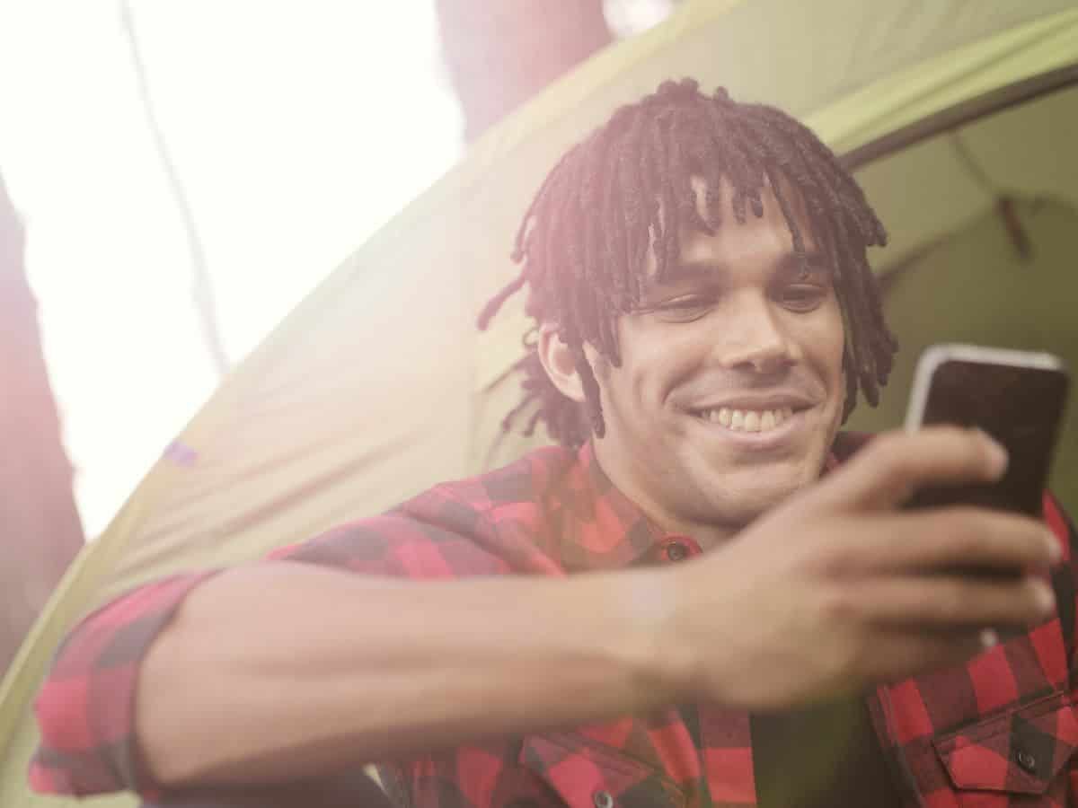 man sitting in green tent on his cell phone