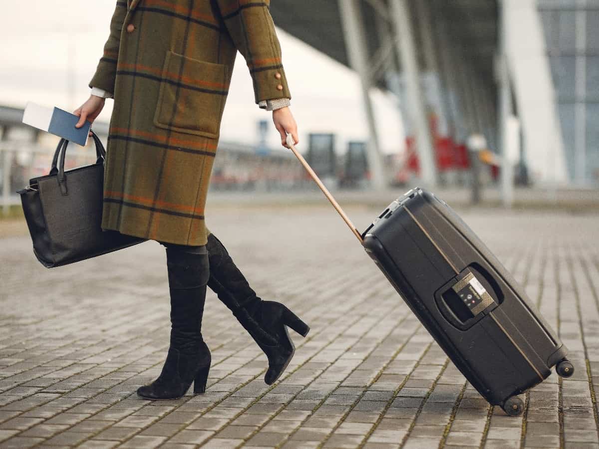 a woman holding a briefcase, passport and luggage