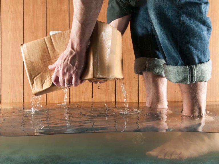 hands picking up a wet cardboard box due a flooded basement without water sensors