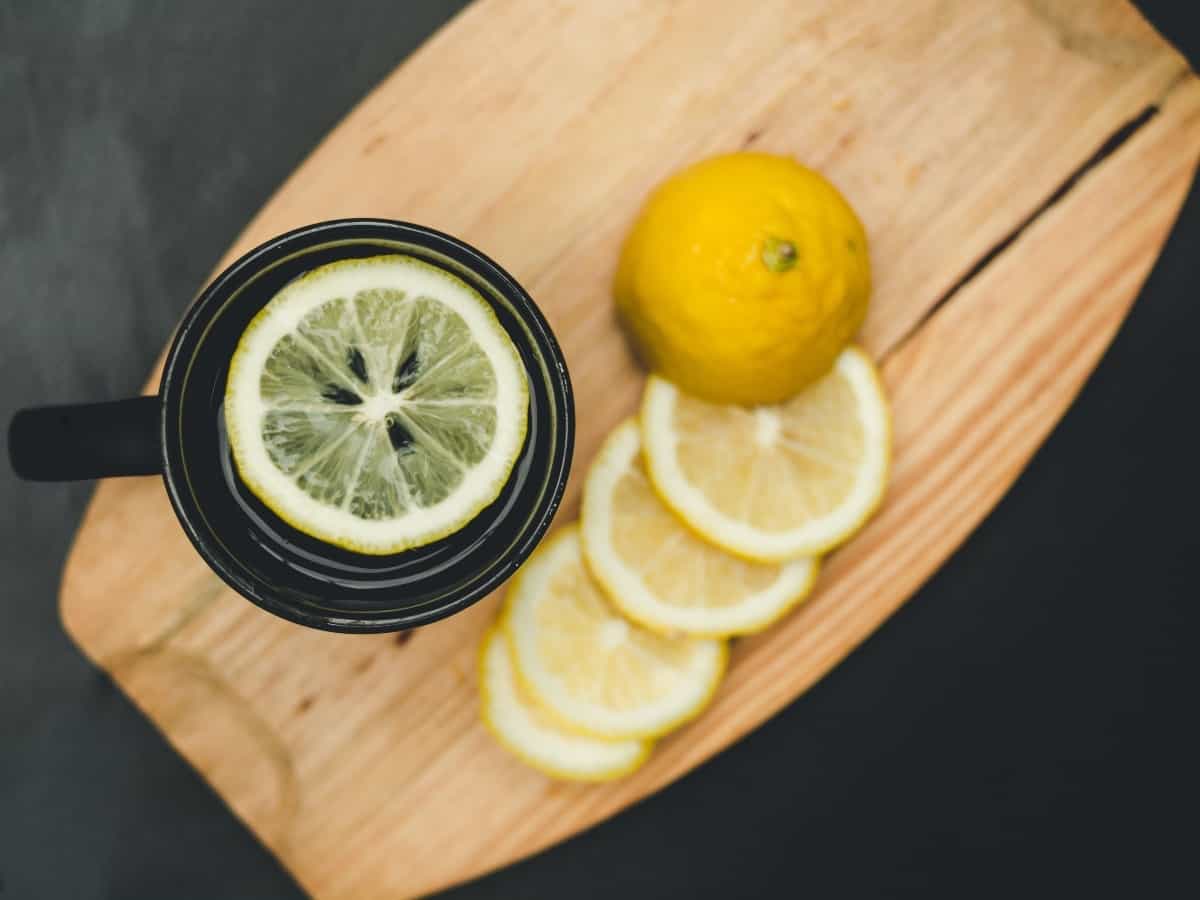 thin lemon slices and hot lemon tea on top of wooden cutting board