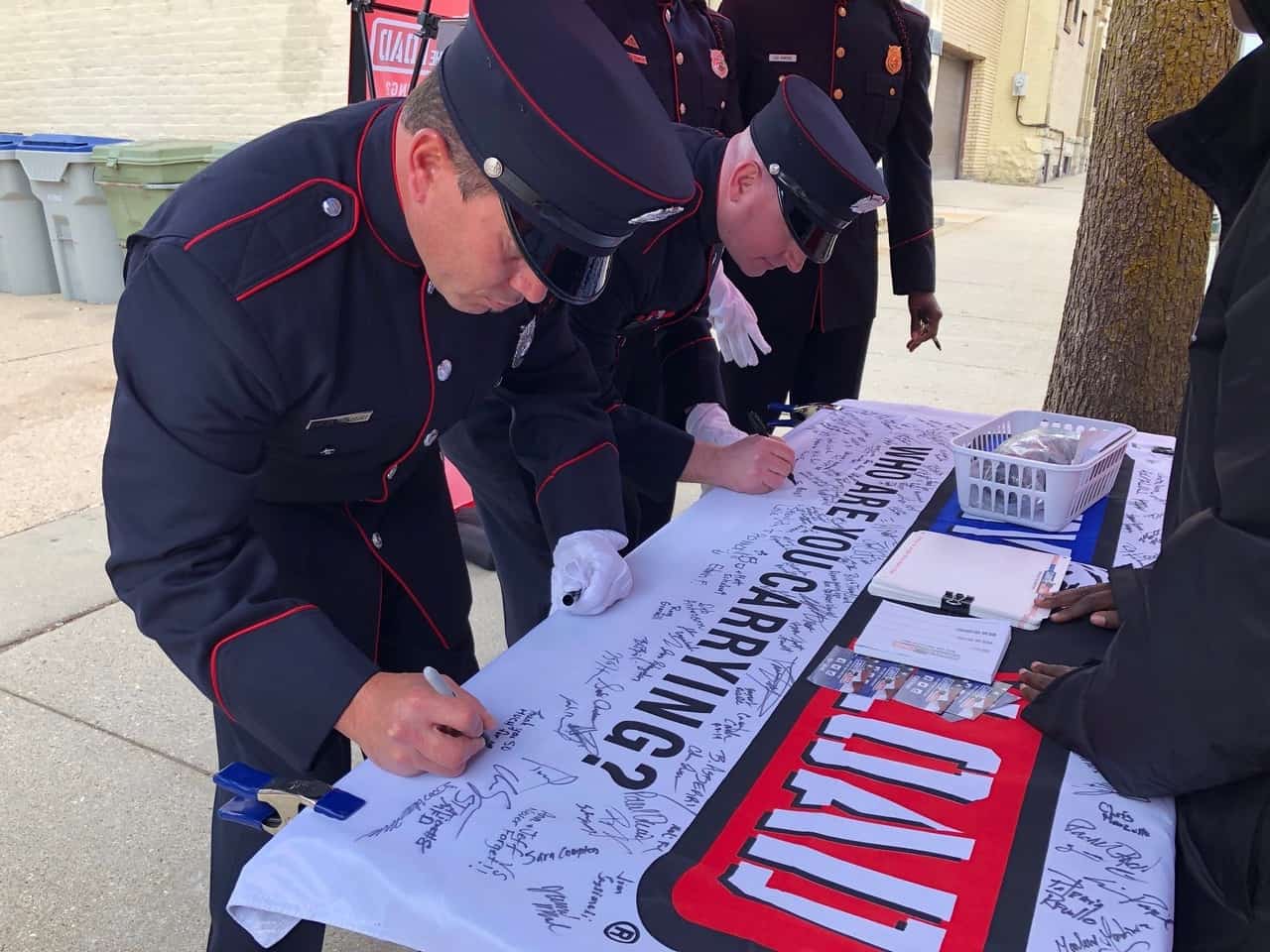 A service member signs his name on a banner on a table at a Carry The Load event.