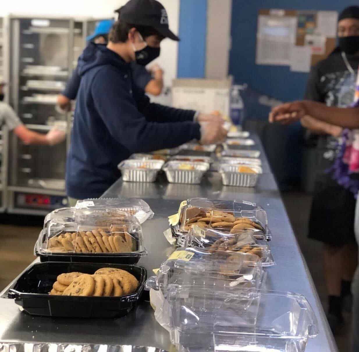 Austin Street Center volunteers are serving food in a kitchen.