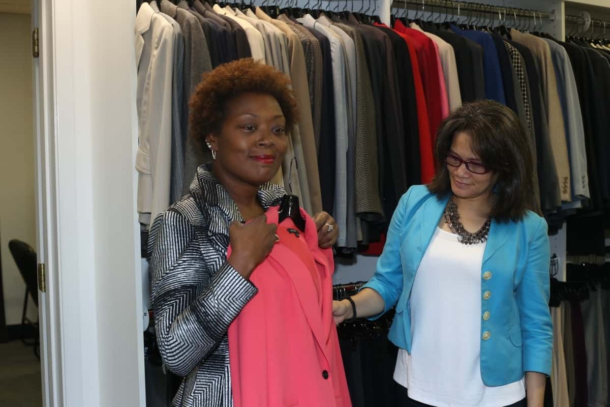 Attitudes and Attire director helps client in boutique.