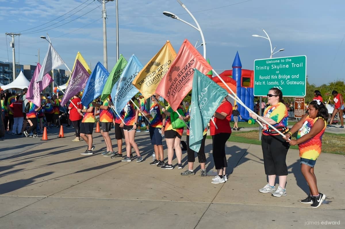 Members of the Cancer Support Community North Texas hold colorful flags outside at an event.