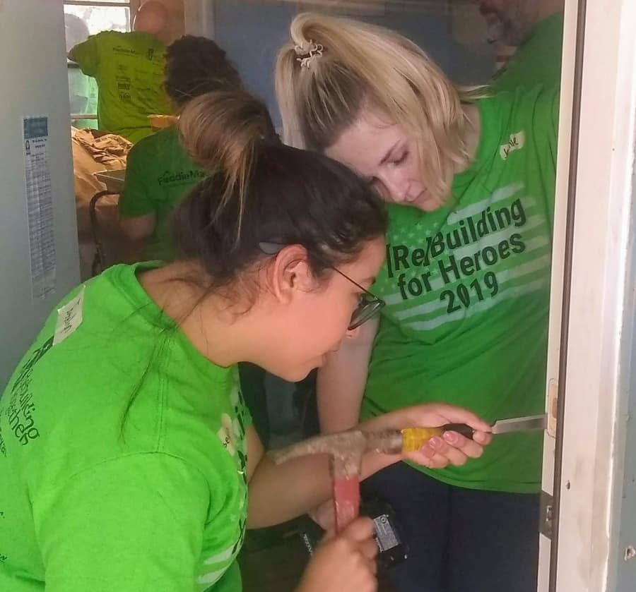 Two volunteers for Rebuilding Together North Texas are working to repair a door inside of a home.