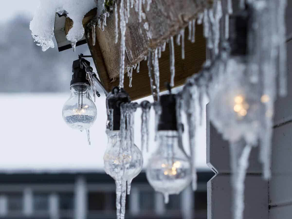 Icicles formed on the eave of a home with lights hanging beneath.