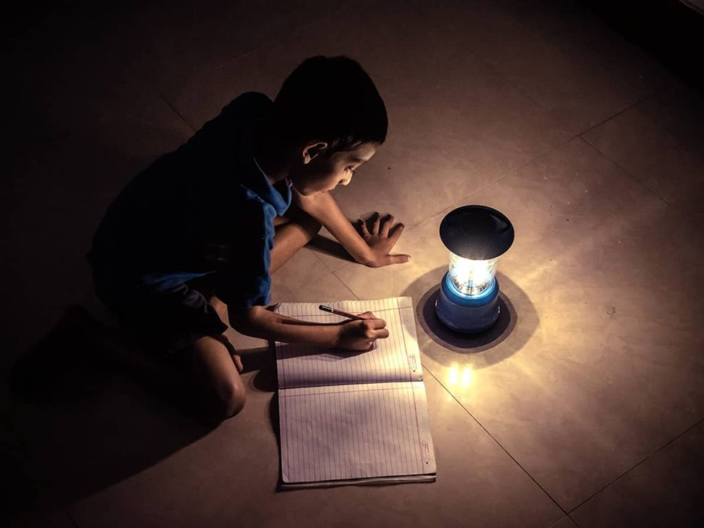 young child reading close to lamp during a rolling blackout