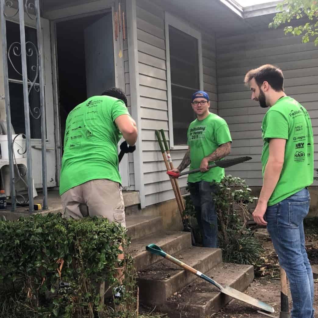 Volunteers for Rebuilding Together North Texas are working outside of a home with shovels in hand.