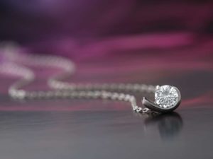 a diamond pendant necklace with purple background jewelry