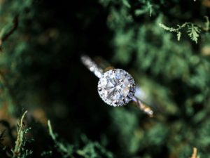 an engagement ring piece of jewelry with green nature in background