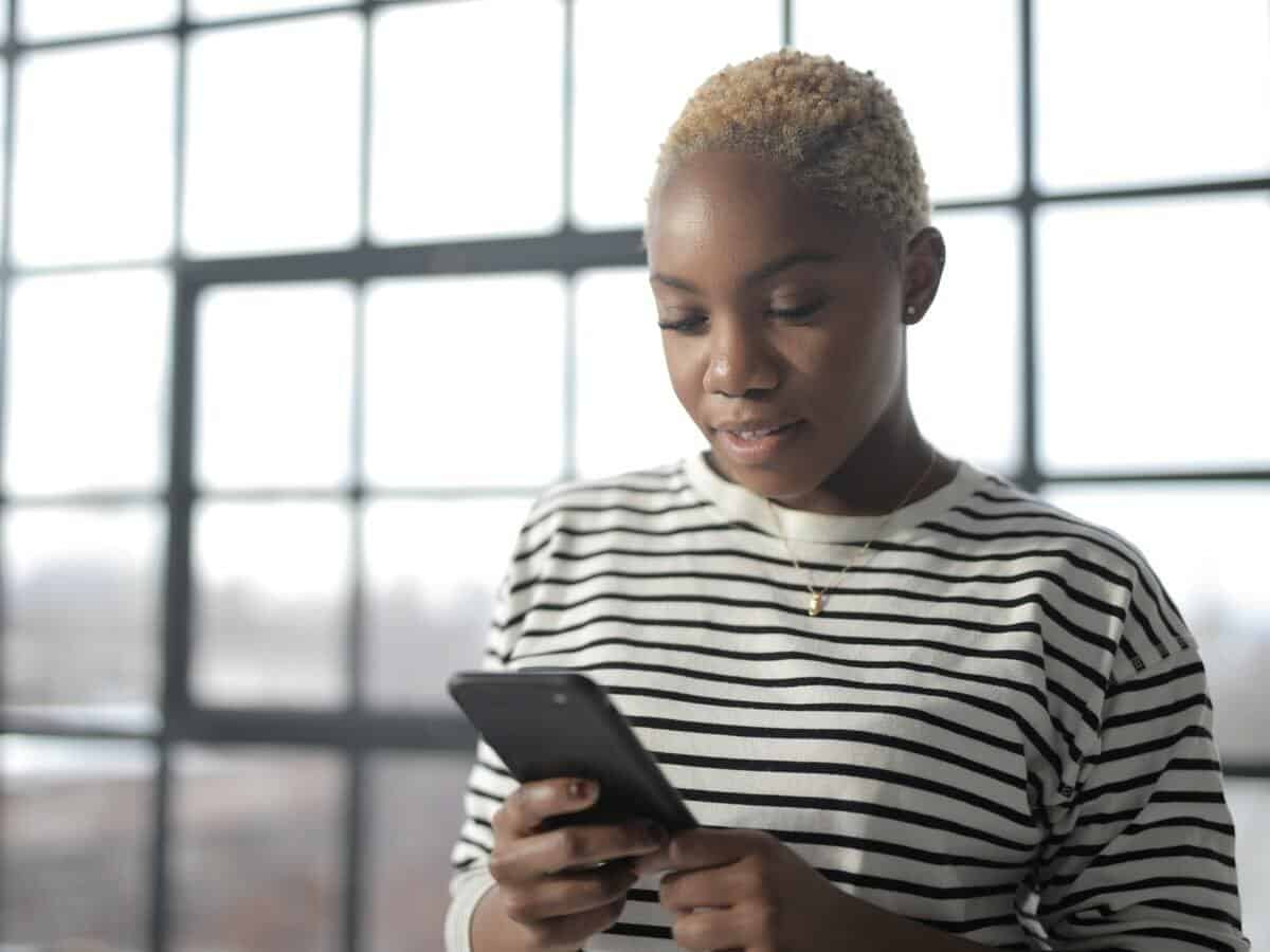 A young woman holds her smartphone to her chest and looks down at the device.