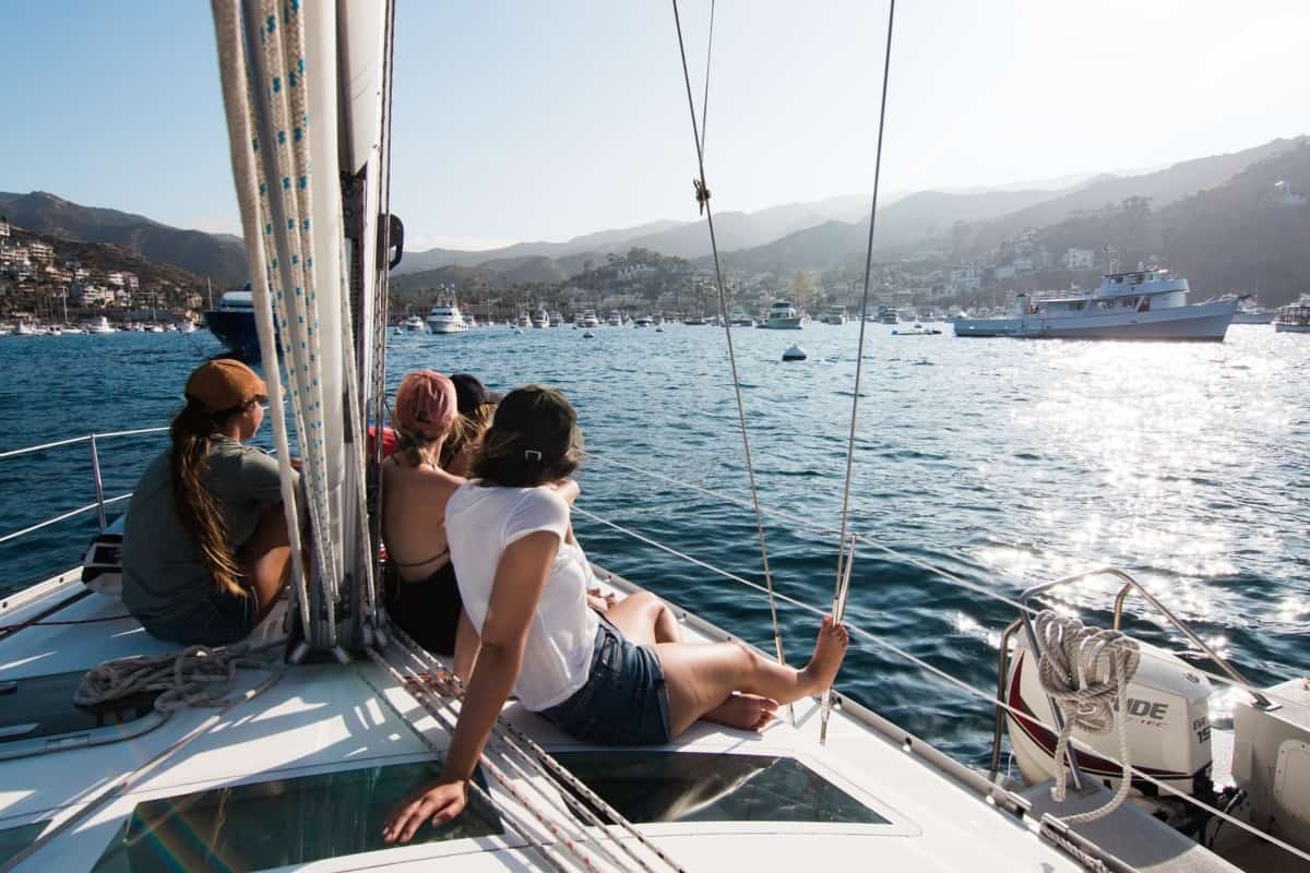 A group of friends sits on a boat that's approaching land on an island.