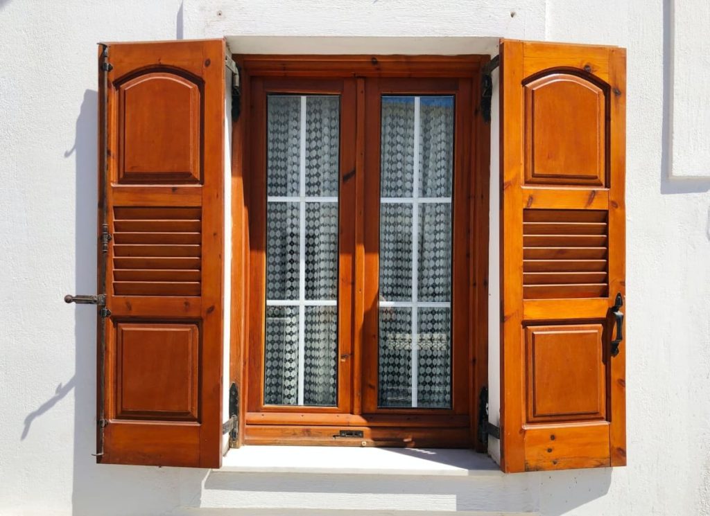 Brown shutters installed on the windows of a white building.
