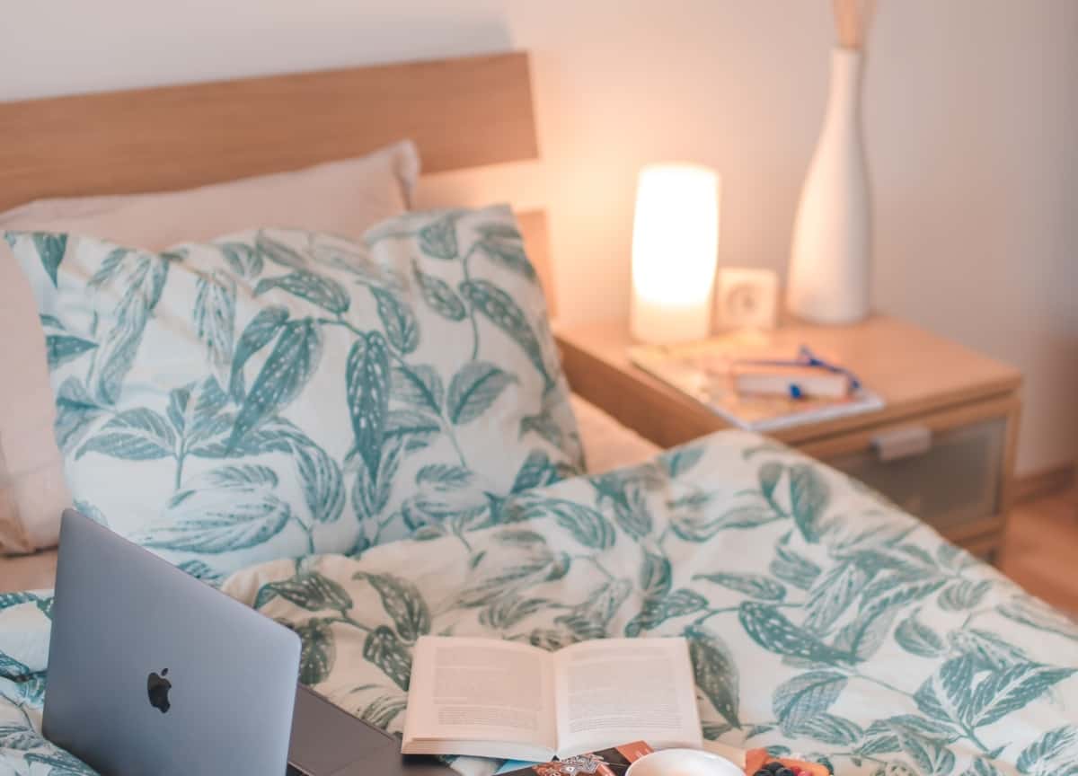 A patterned comforter is on a bed inside of a modern bedroom.