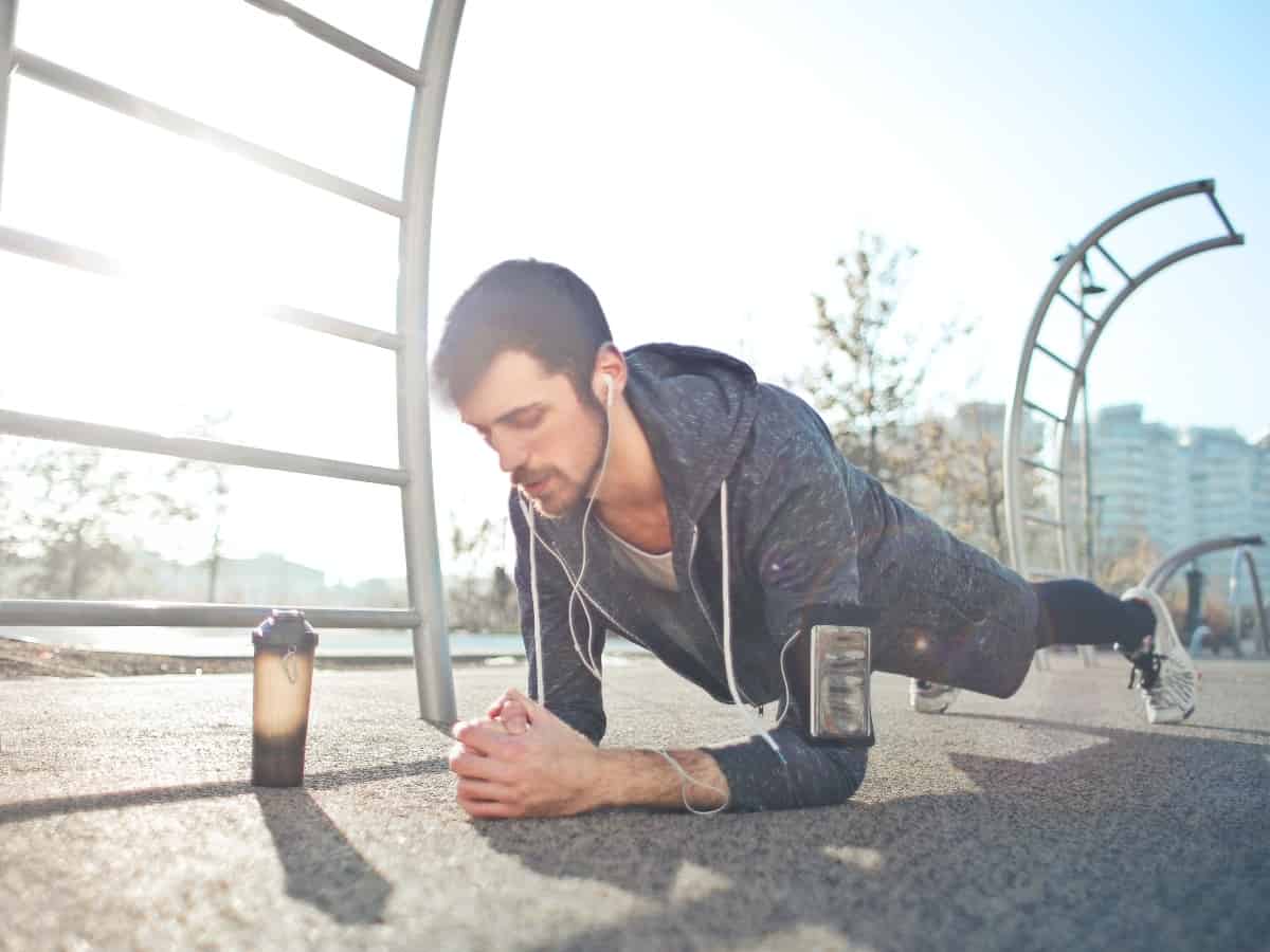 man doing plank workout with a water bottle or shaker bottle next to him