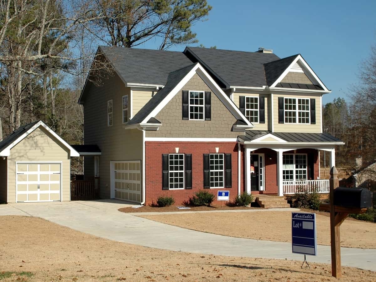 a two story house with detached garage with a for sale sign