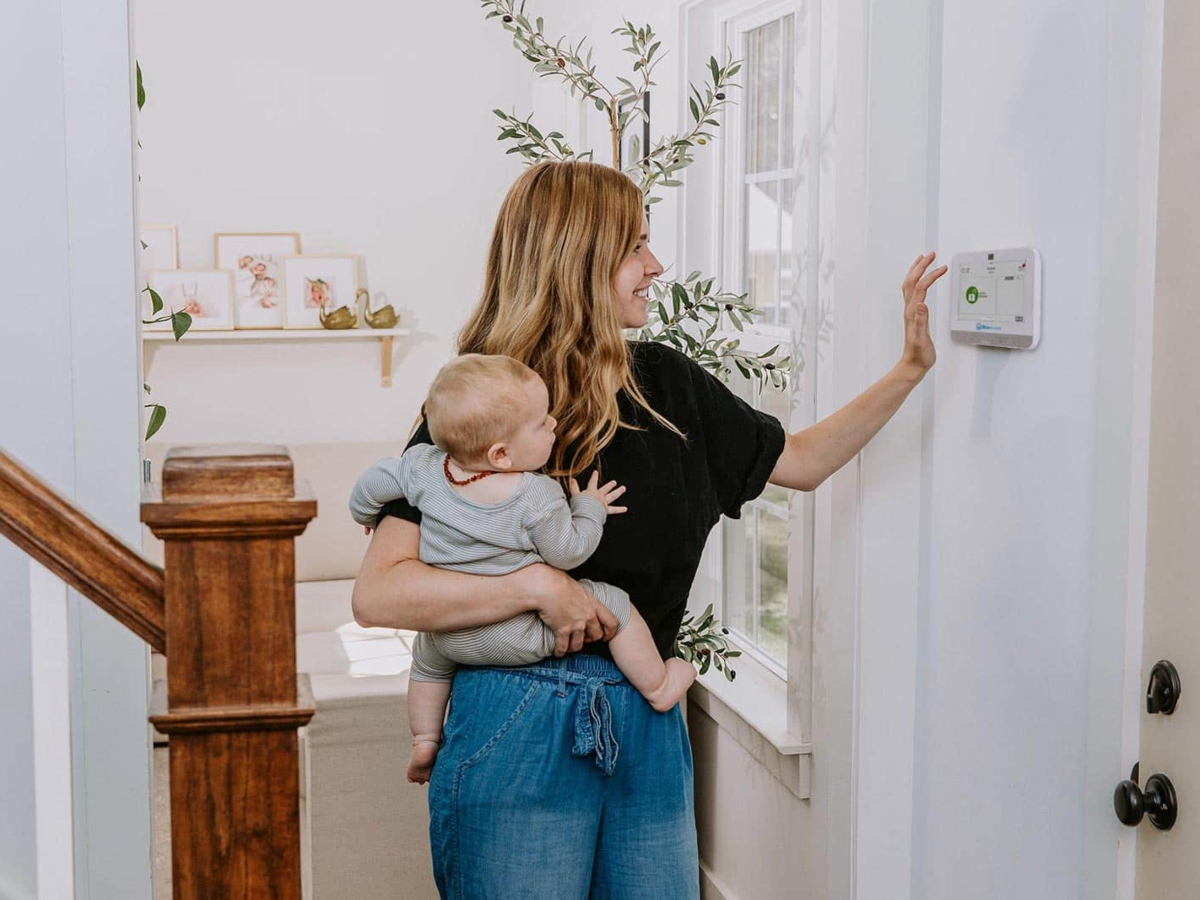 a woman holding her child in front of a home security system