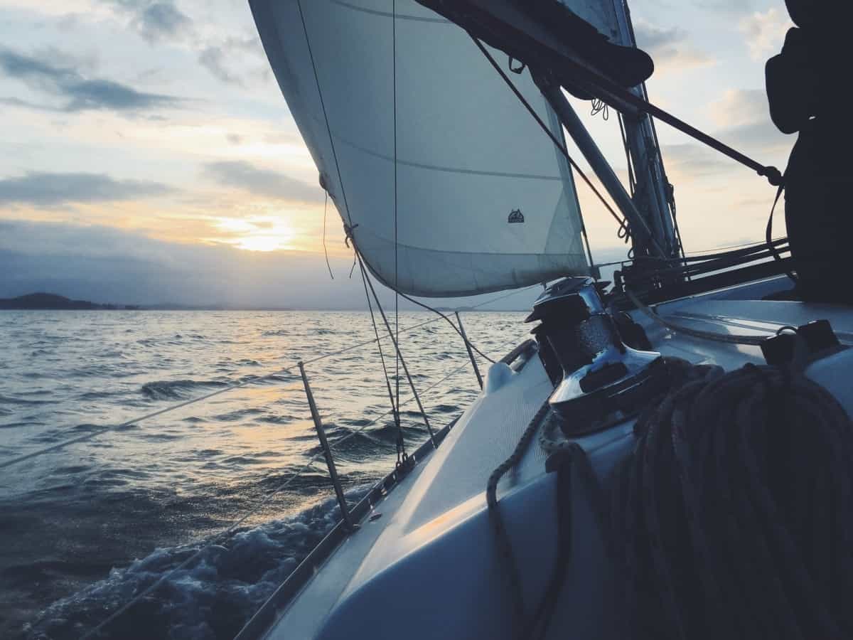 A view of a boat's interior and sails as it cruises in the water.