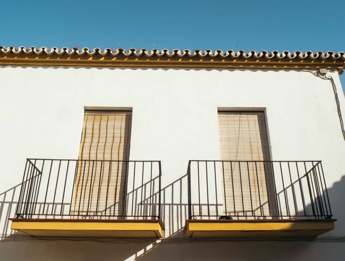 Light brown hurricane shutters installed on the windows of a balcony.