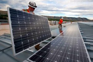 A team is installing solar panels on a roof outside.