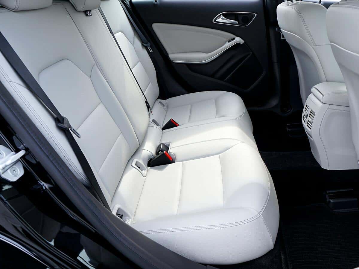 The back seat of a car with white leather seats.