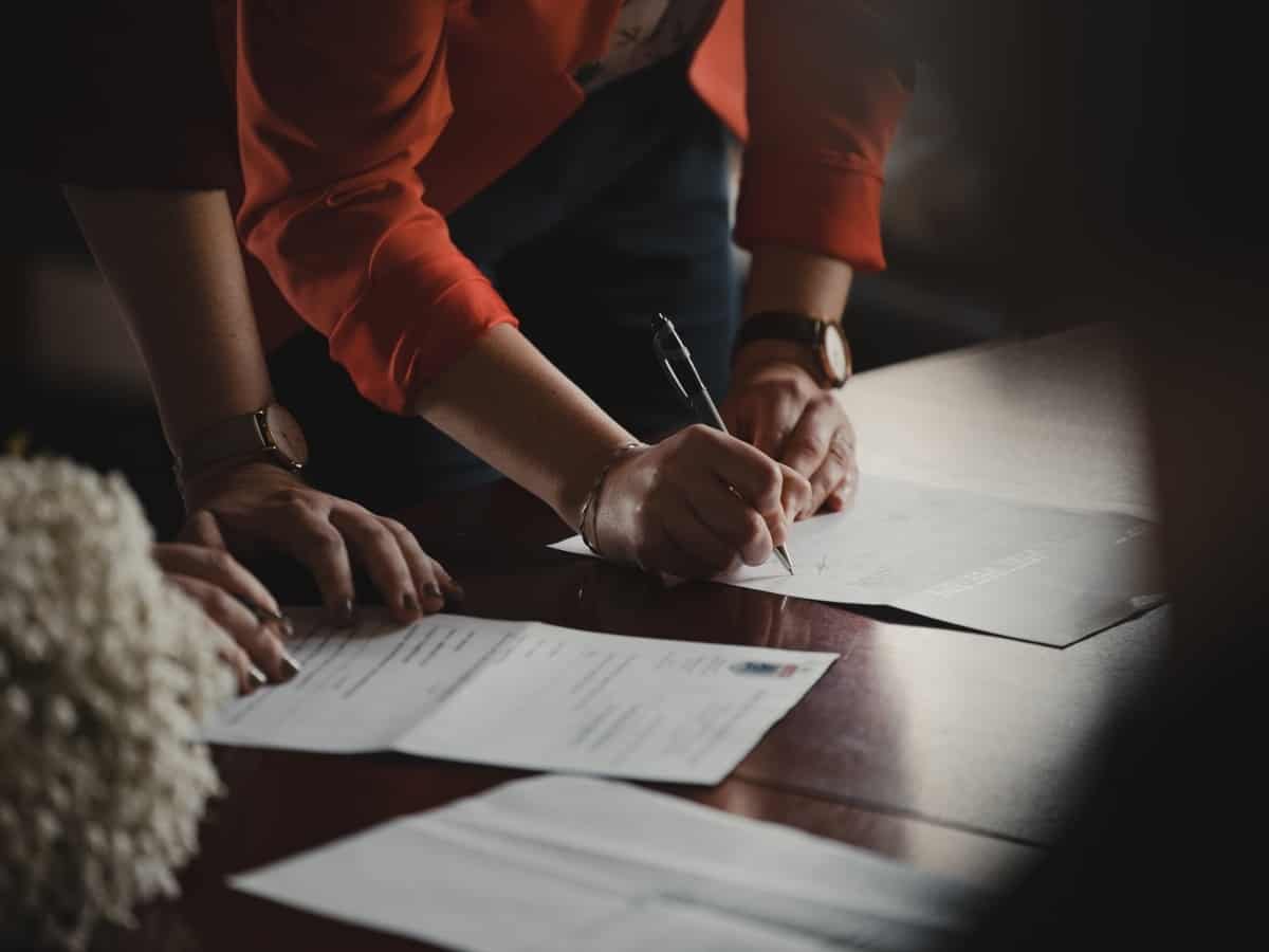 A man and woman in professional clothing are filling out a document.