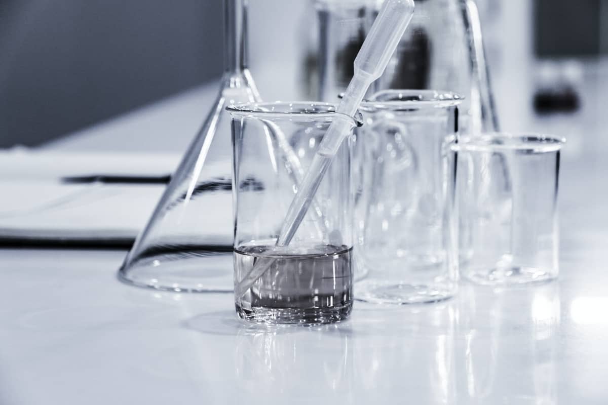 Glass beakers with water inside are sitting on a white surface.