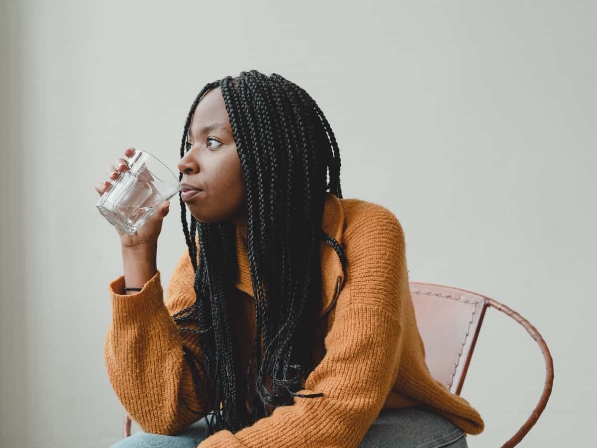 woman drinking a healthiest type of water to drink out of a glass