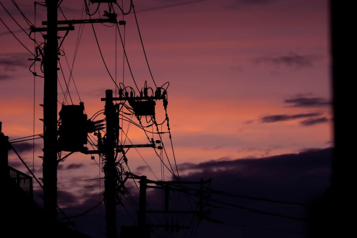 Tall power lines standing outside under a pink and purple sky.