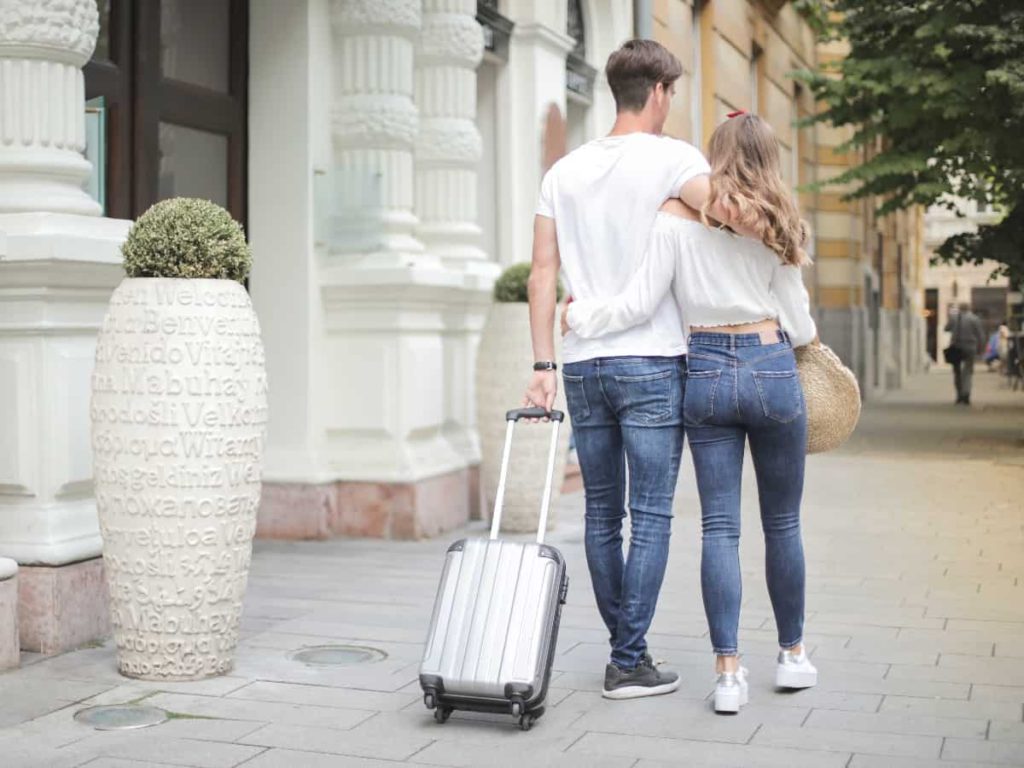 two people walking together with the luggage behind them while traveling