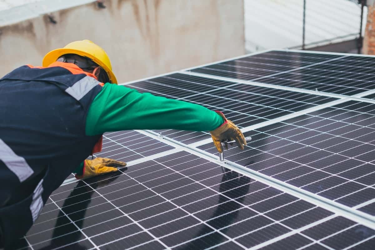 A technician is installing solar panels on the roof of a property.
