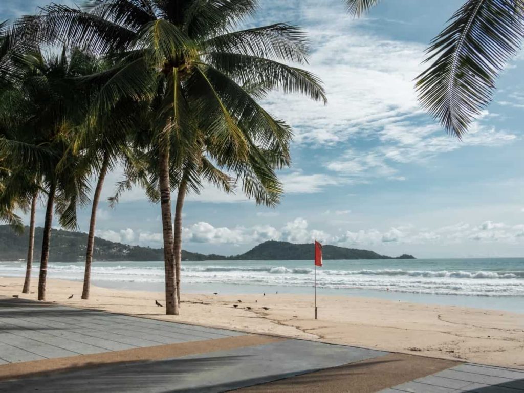 a red flag on the beach indicating high waves, due to a tropical storm vs hurricane season and keeping citizens out of the ocean