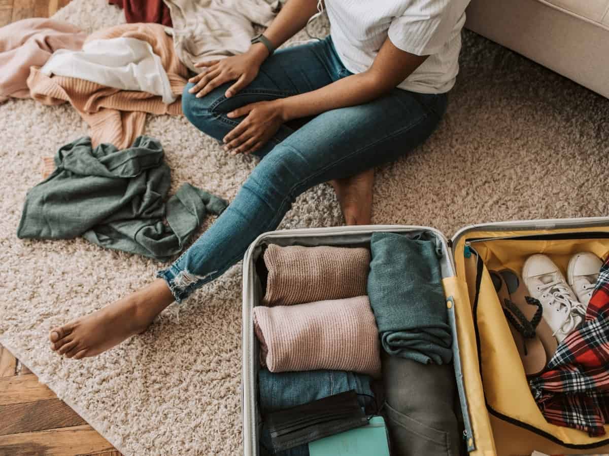 girl sitting on the ground with her luggage and clothing out on the ground