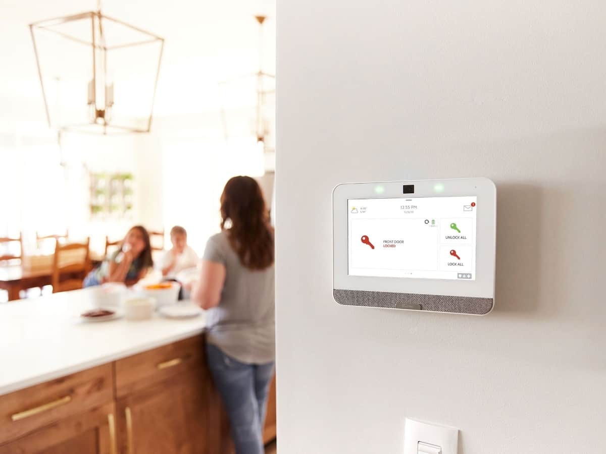 a woman in the kitchen cooking with the qolsys iq panel in the background on the wall