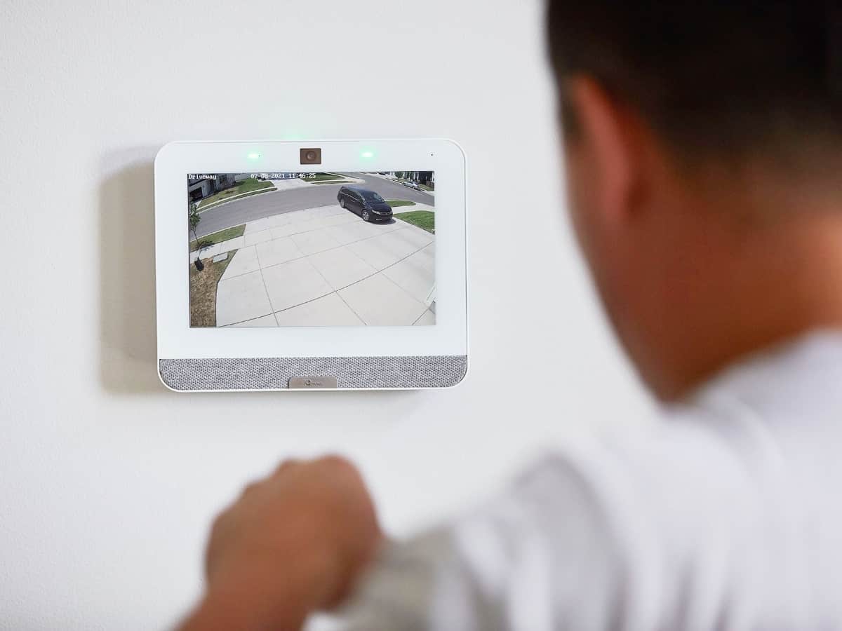 a man looking at the qolsys iq panel 4 as someone drives off the driveway at home for security