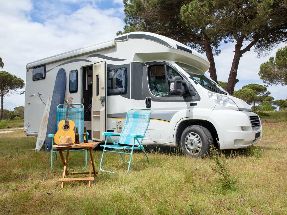 the exterior view of a travel trailer with two chairs and a guitar 