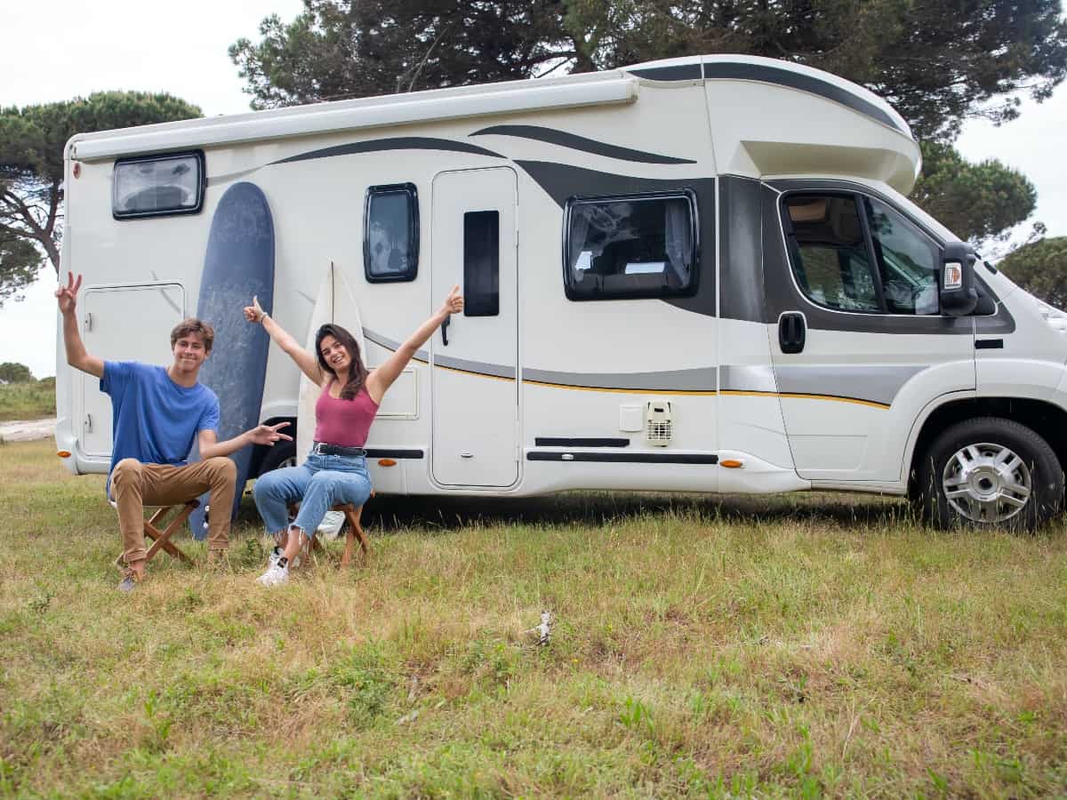 a couple sitting outside their travel trailer in the daytime on a roadtrip