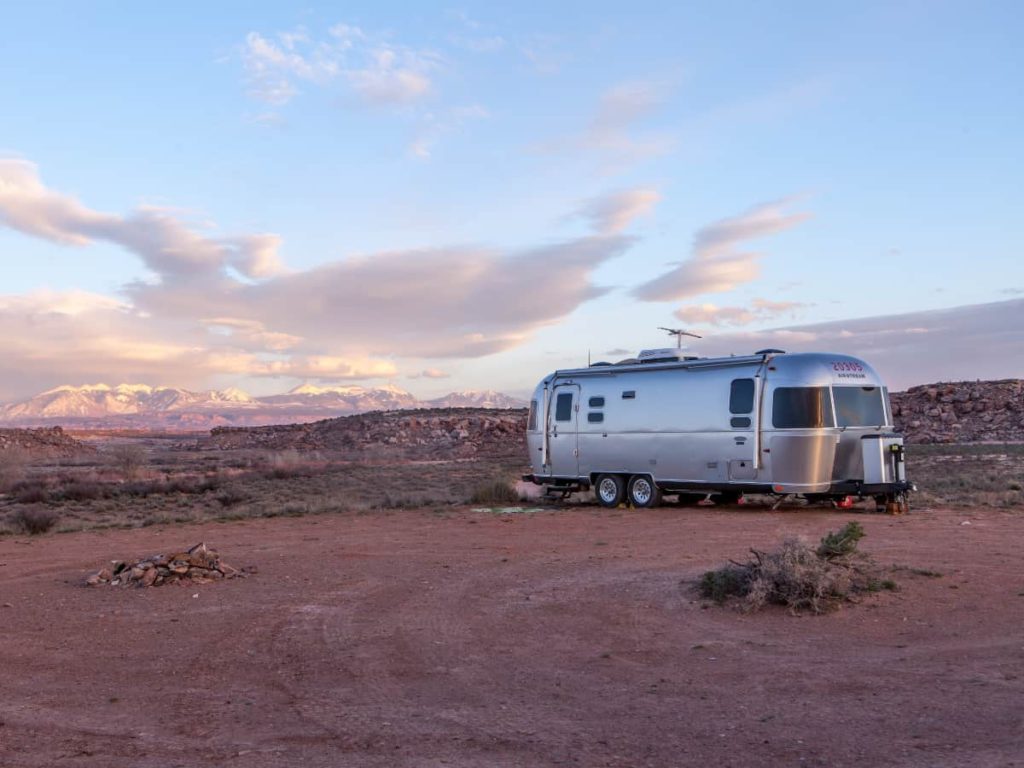 an exterior view of a sunset or sunrise and a travel trailer parked on a beach