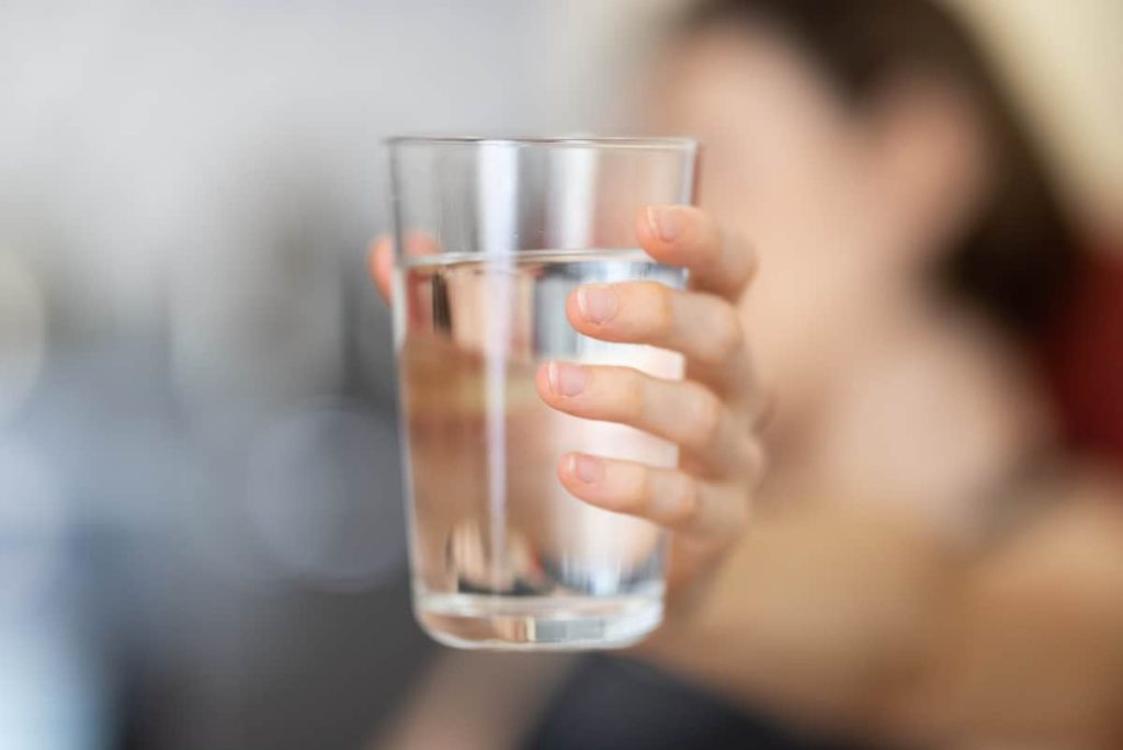 Hand holding a full glass of water.