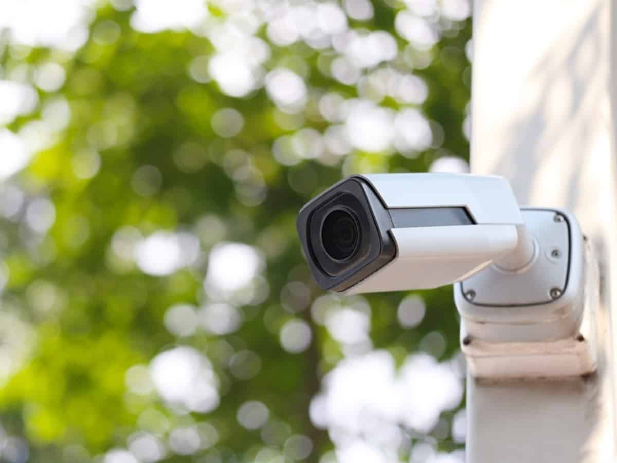 a security camera on the side of a house with trees in the background