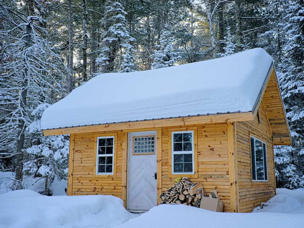 small home with roof covered in snow in the middle of winter
