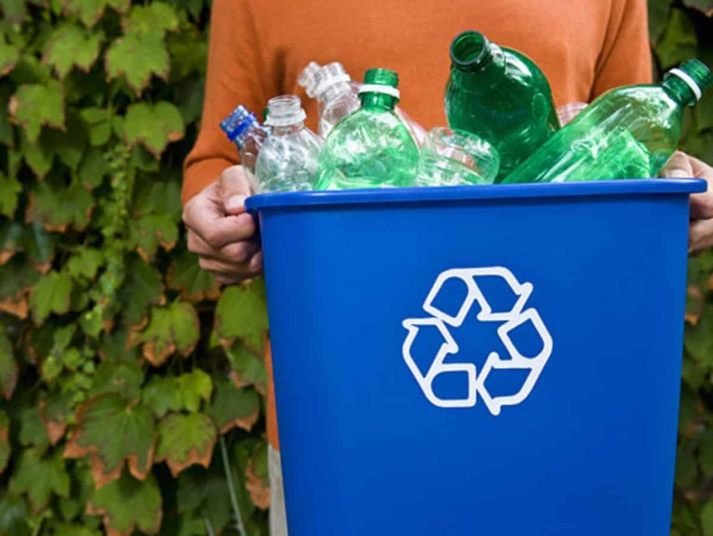 a trash can filled with plastic bottles and a recycle logo on the front