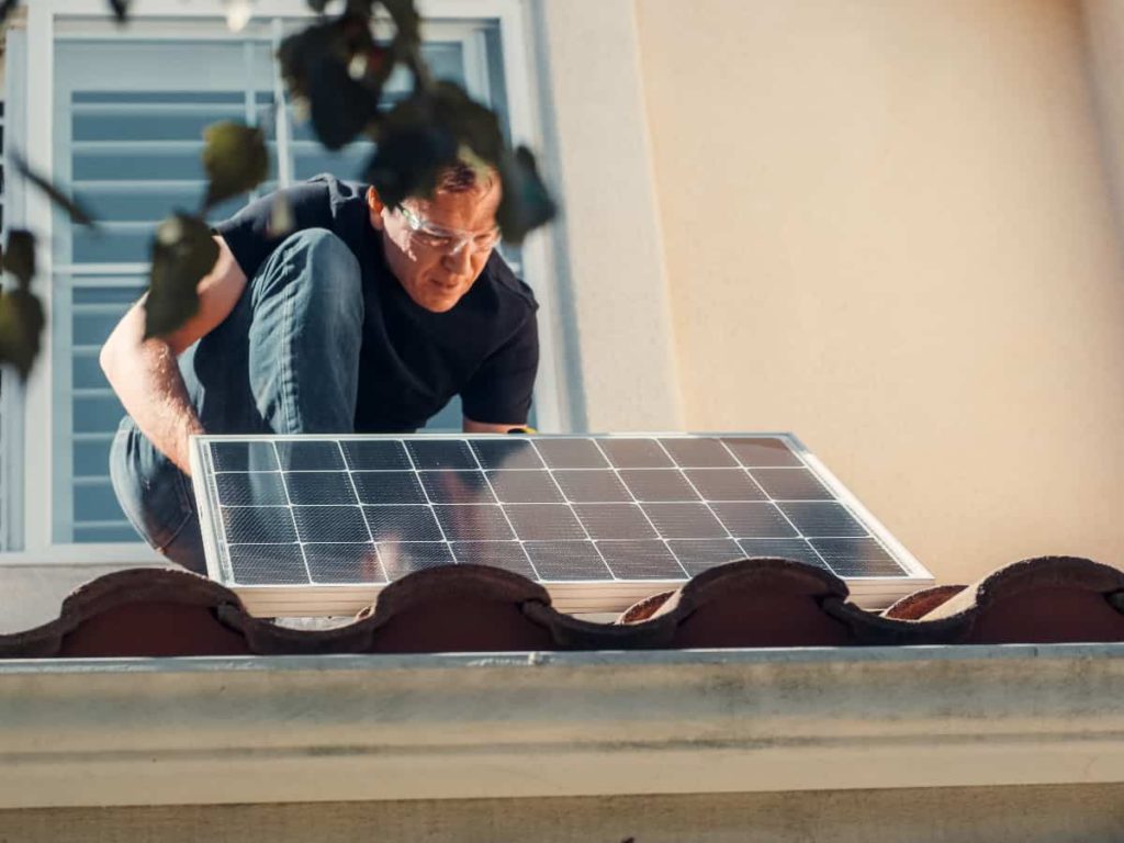 a man on a roof installing a solar panel