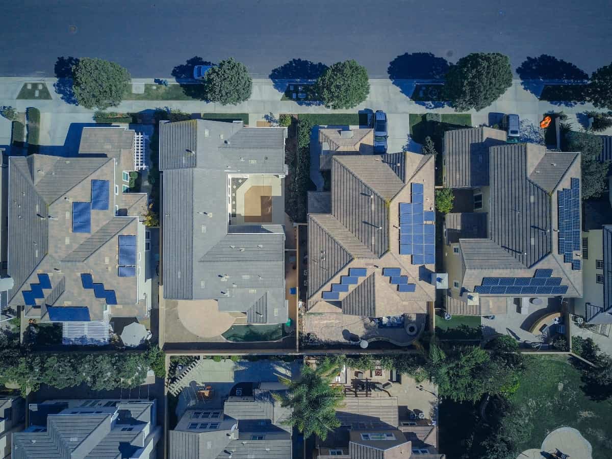 an aerial view of solar panels on a roof in a home and neighborhood on multiple households