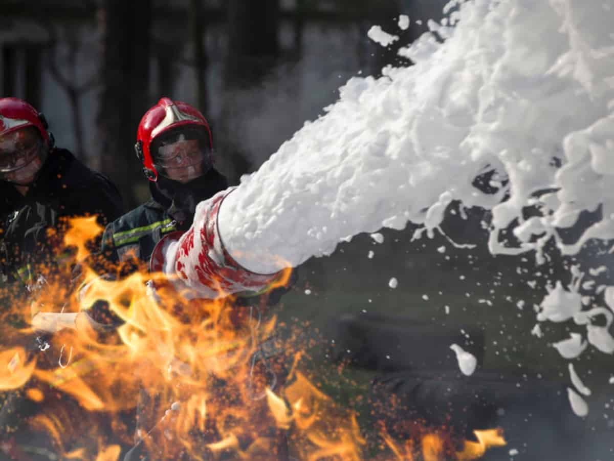 firefighters putting out a fire with foam linked to PFAS contamination