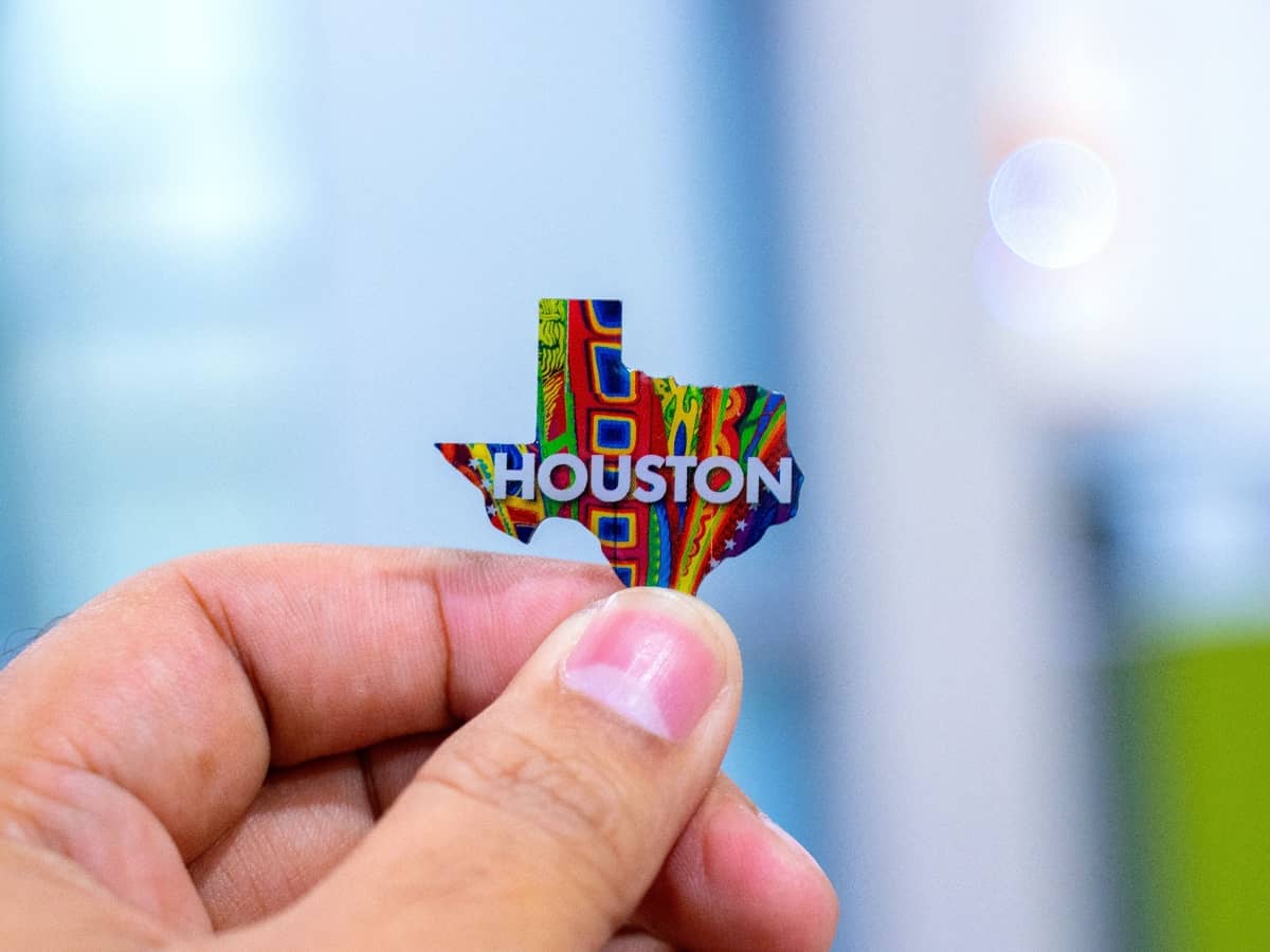 a hand holding a texas state pin with houston written across it